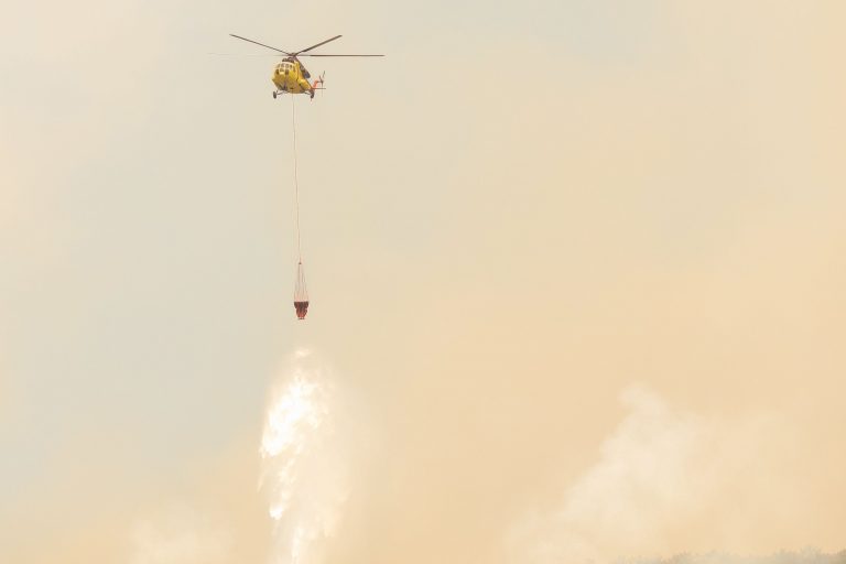 Imagen de recurso de un helicóptero descargando agua sobre un incendio forestal