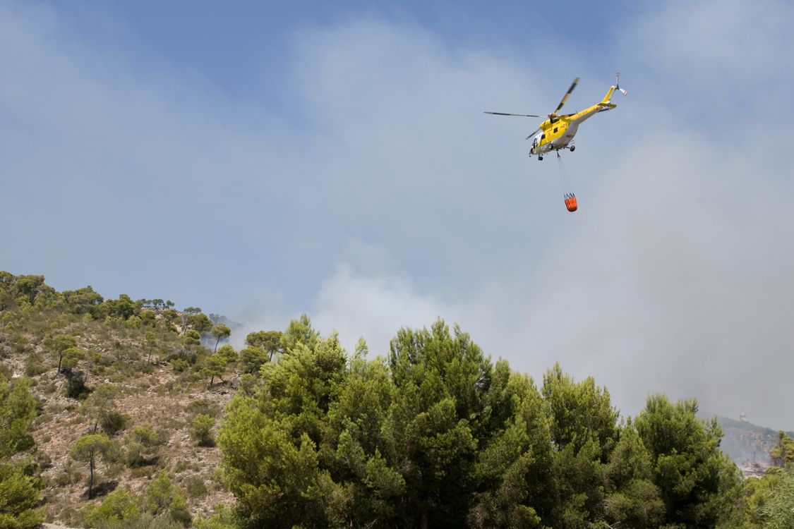 Helicóptero de extinción sobre una zona forestal, imagen de recurso
